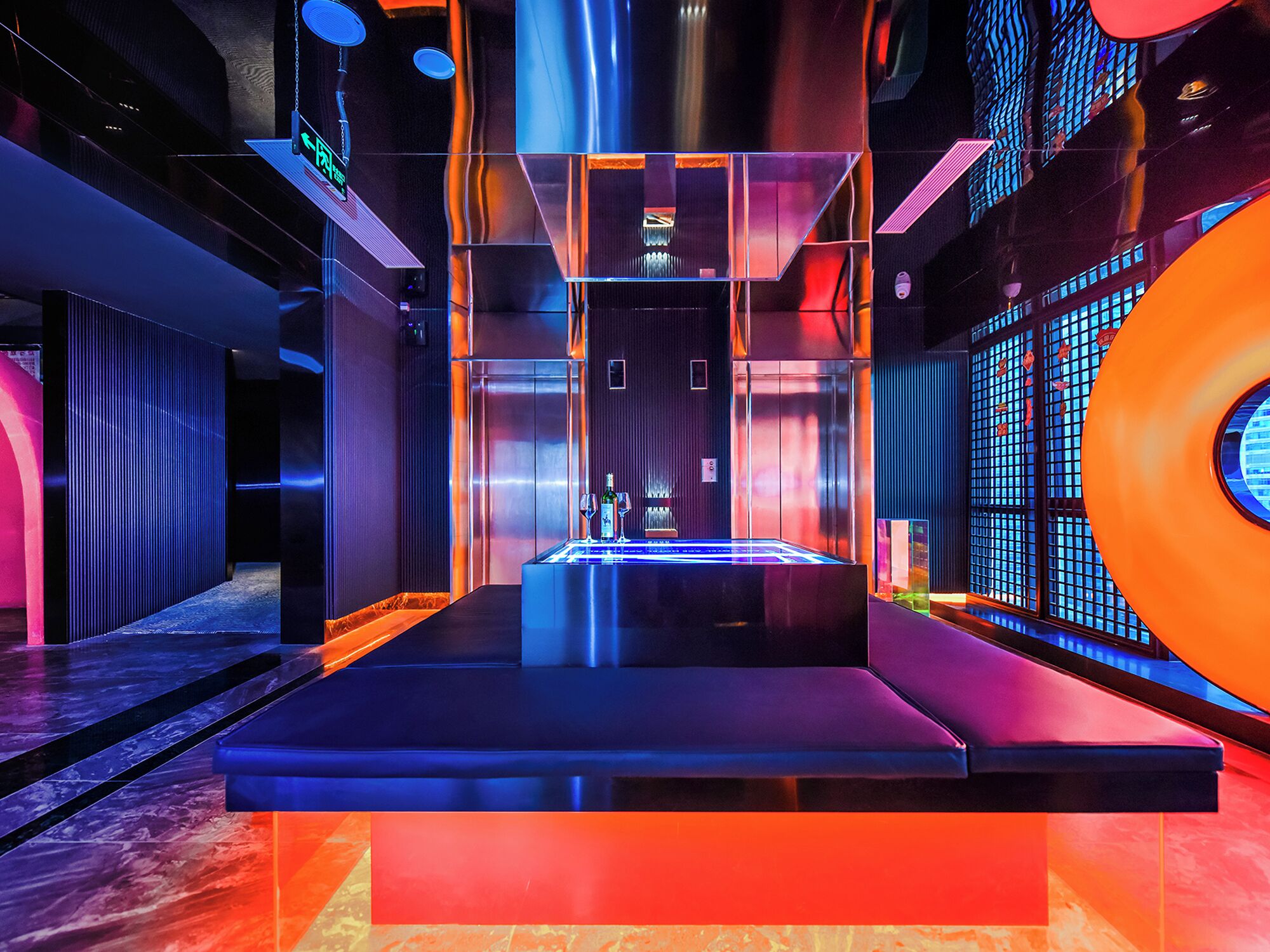 Un interior moderno con una plataforma central, ascensor metálico y un muro estampado con un ventanal circular.