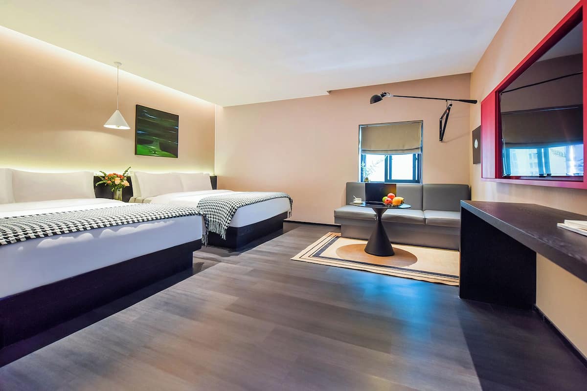 Ein modernes Hotelzimmer mit einem großen Bett, einer Sitzecke, einem Schreibtisch und einem großen Fenster.