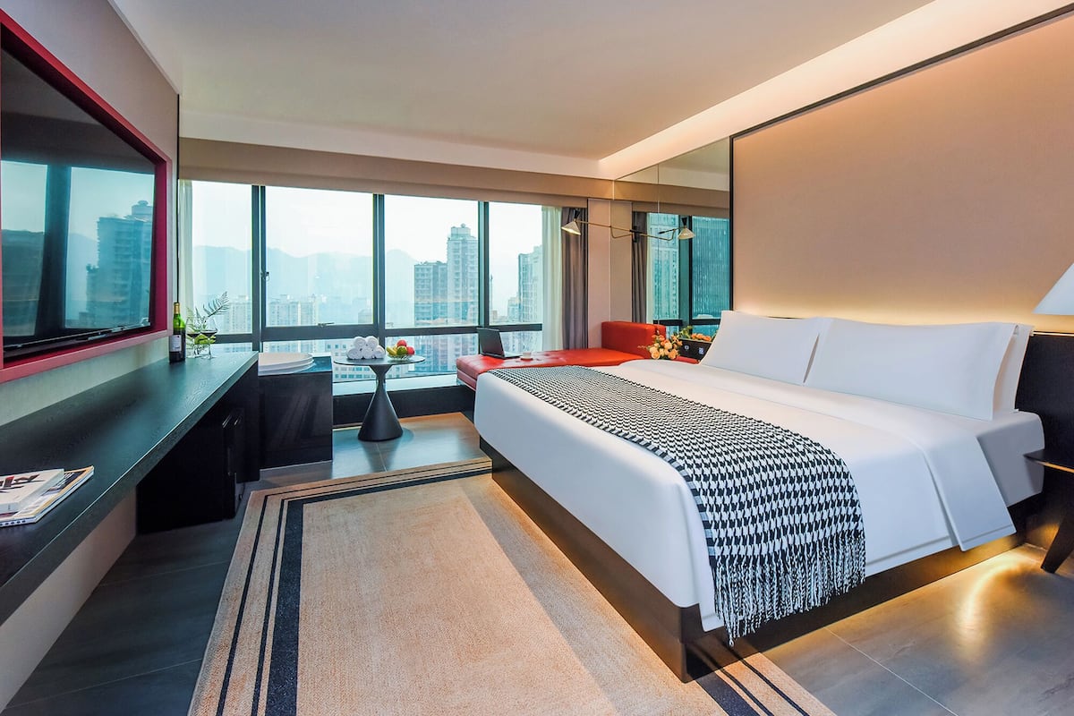 Ein modernes Hotelzimmer mit einem großen Bett, einem Schreibtisch und Blick auf die Stadt.