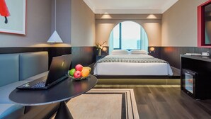 Et moderne hotelværelse med en seng, en bærbar computer på et bord og en skål med frugt.