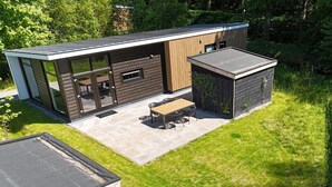Ein modernes Haus mit Terrasse, Essbereich und überdachter Außenausstattung.