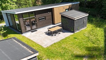 Een modern huis met een terras, een eethoek en een overdekte buitenruimte.
