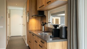 Eine moderne Küche mit Holzausstattung, einer Edelstahl-Spüle und einer Kaffeemaschine.
