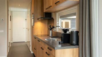 Een moderne keuken met houten kastjes, een roestvrijstalen spoelbak en een koffiezetapparaat.