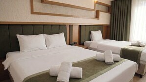 A hotel room with two beds, a headboard, a wall-mounted light, and a window with curtains. - MONTELLA HOTEL (Elbistan)