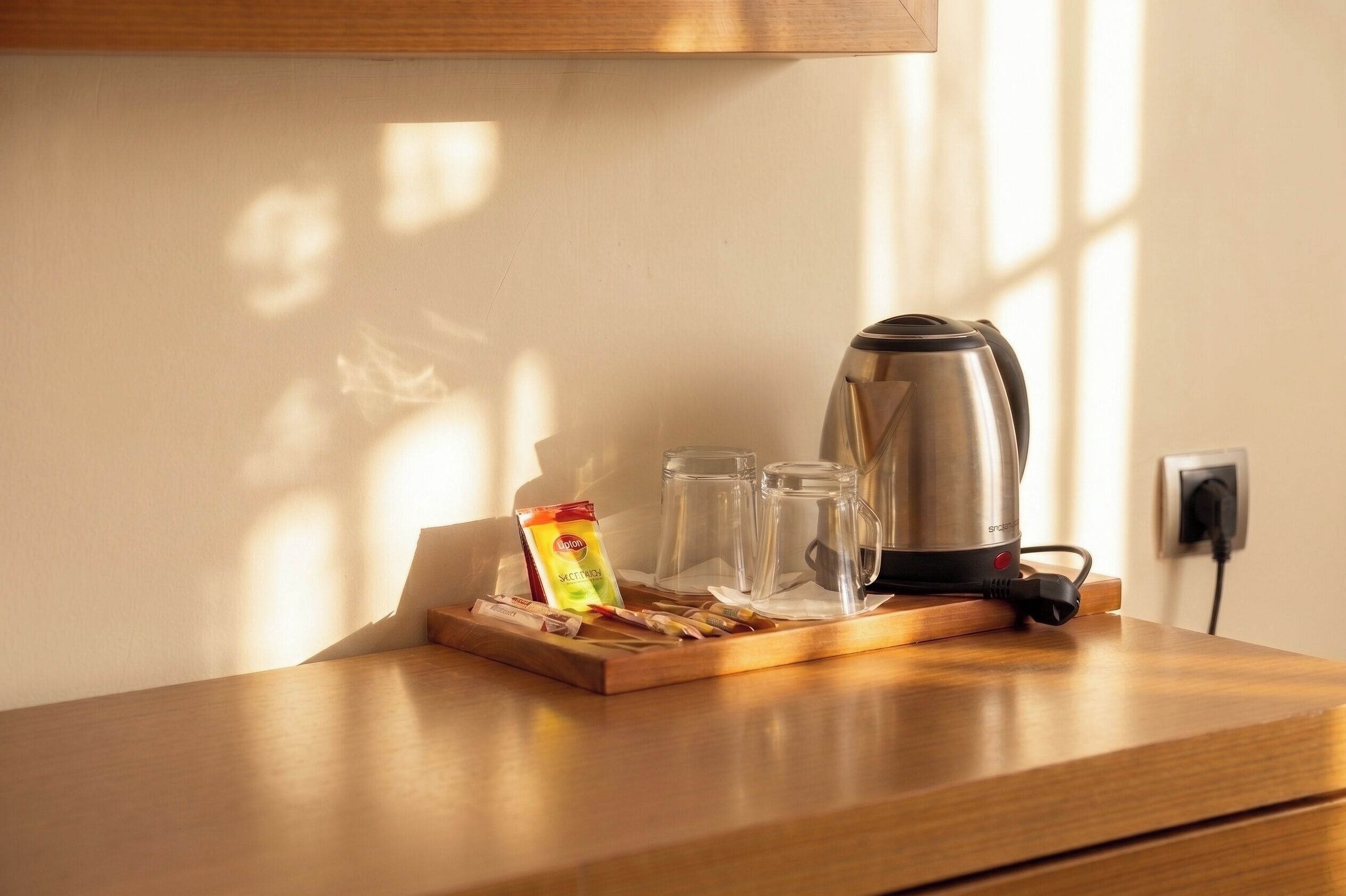 A kitchen counter with a kettle, glasses, and a packet of tea.