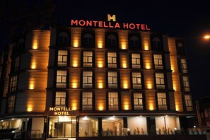Un hôtel à plusieurs étages dont la façade est ornée d’une enseigne lumineuse indiquant « MONTELLA HOTEL ».