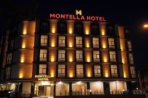 Um hotel de vários andares com letreiros iluminados com a inscrição "MONTELLA HOTEL" e "MONTELLA HOTEL" na fachada.