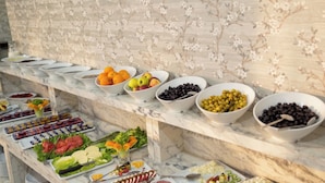 A buffet with various food items and a floral wall in the background. - MONTELLA HOTEL (Elbistan)