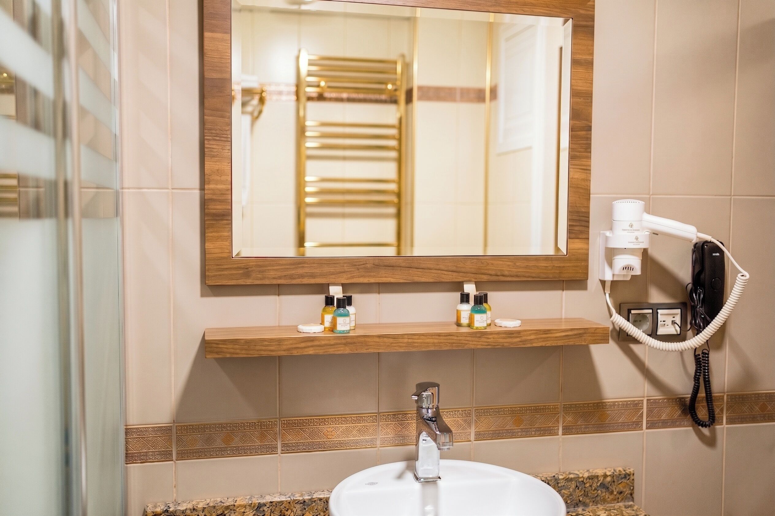 Un baño con lavamanos, espejo, toallero y teléfono.