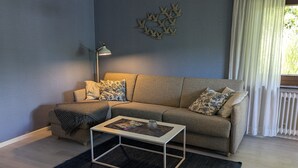 Una sala de estar con sofá, una mesita de centro, una lámpara y una decoración en la pared.