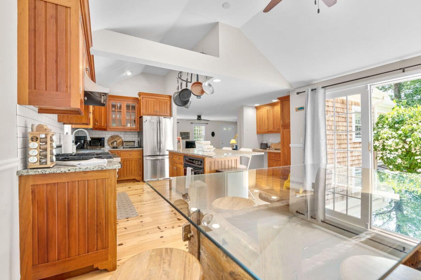 A modern kitchen with wooden cabinets, stainless steel appliances, and a glass dining area.