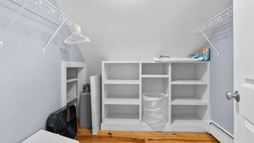 A small, narrow hallway with white shelving units and a clear plastic storage bin.