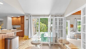 A modern kitchen with wooden cabinets, a stainless steel dishwasher, and a large window overlooking a garden. - Gorgeous Home 1 mile to Beach, by Cape Cod Bikepath (Dennis)