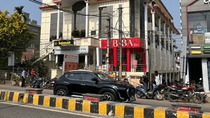 Un immeuble à plusieurs étages, sur lequel on peut voir une enseigne indiquant « Hôtel City Palace », ainsi qu’un magasin BBA et un magasin Canon.