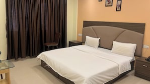 Une chambre d’hôtel avec un grand lit, une table de chevet, une chaise et une fenêtre avec des rideaux.