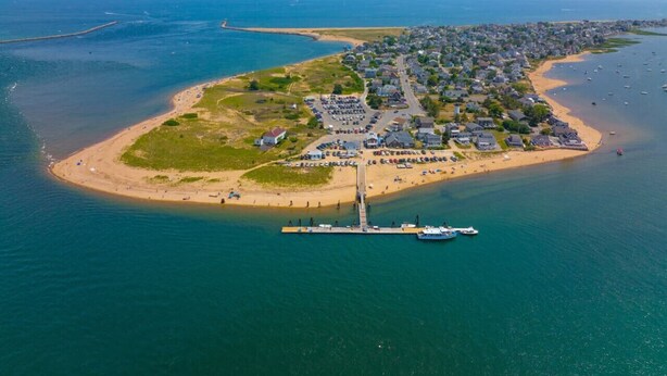 An aerial view of a coastal town with a prominent pier, sandy beaches, and residential buildings.