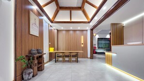A modern interior with a wooden reception desk, a dining area with a table and chairs, and a tiled floor. - Phoenix Haven (Xiangxi)
