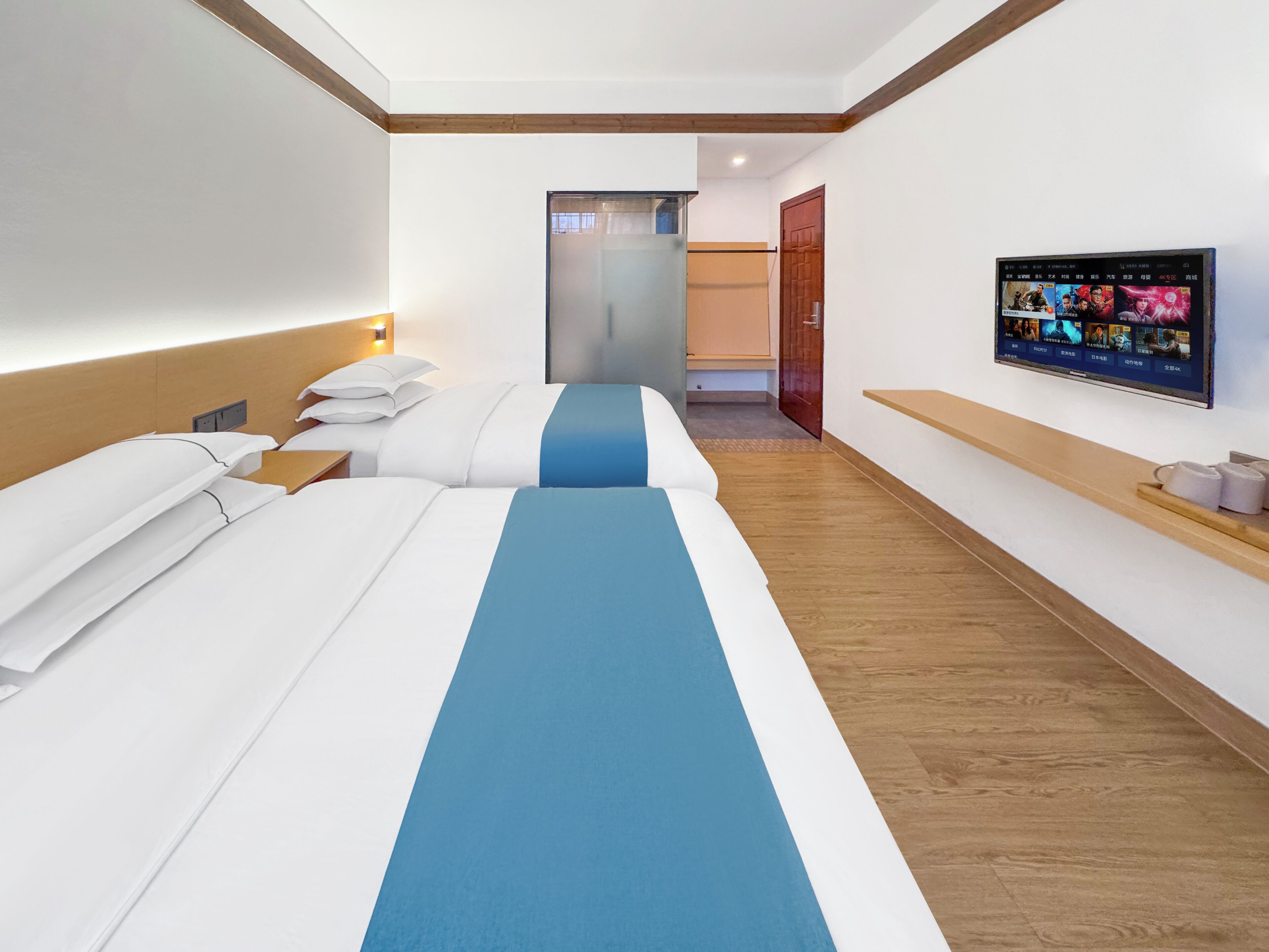 Habitación de hotel con dos camas, un televisor en la pared y suelo de madera.