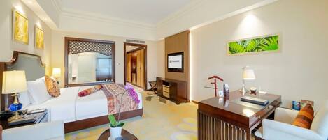 A hotel room with a bed, a desk, a chair, a coffee table, and a TV.
