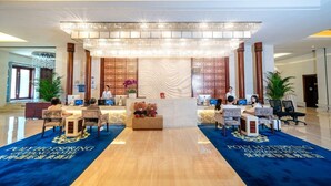 Een hotellobby met een receptiebalie, diverse computerwerkplekken en een grote kroonluchter.