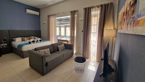 Een hotelkamer met een bed, een bank, een televisie en een schilderij aan de muur.
