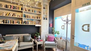 Een gezellig leeshoekje met een grote kroonluchter, boekenkasten, een bank en een bureau met een kaart.