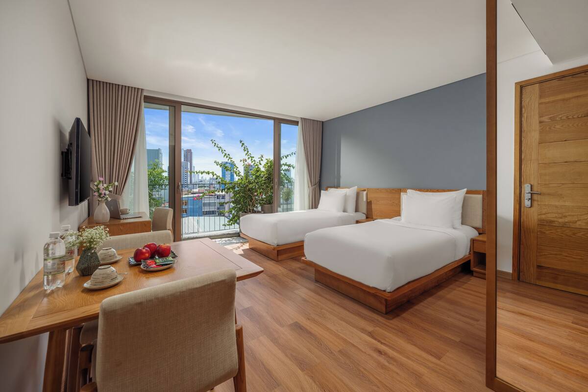 Une chambre d’hôtel moderne équipée de deux lits, d’une table à manger et d’un téléviseur.