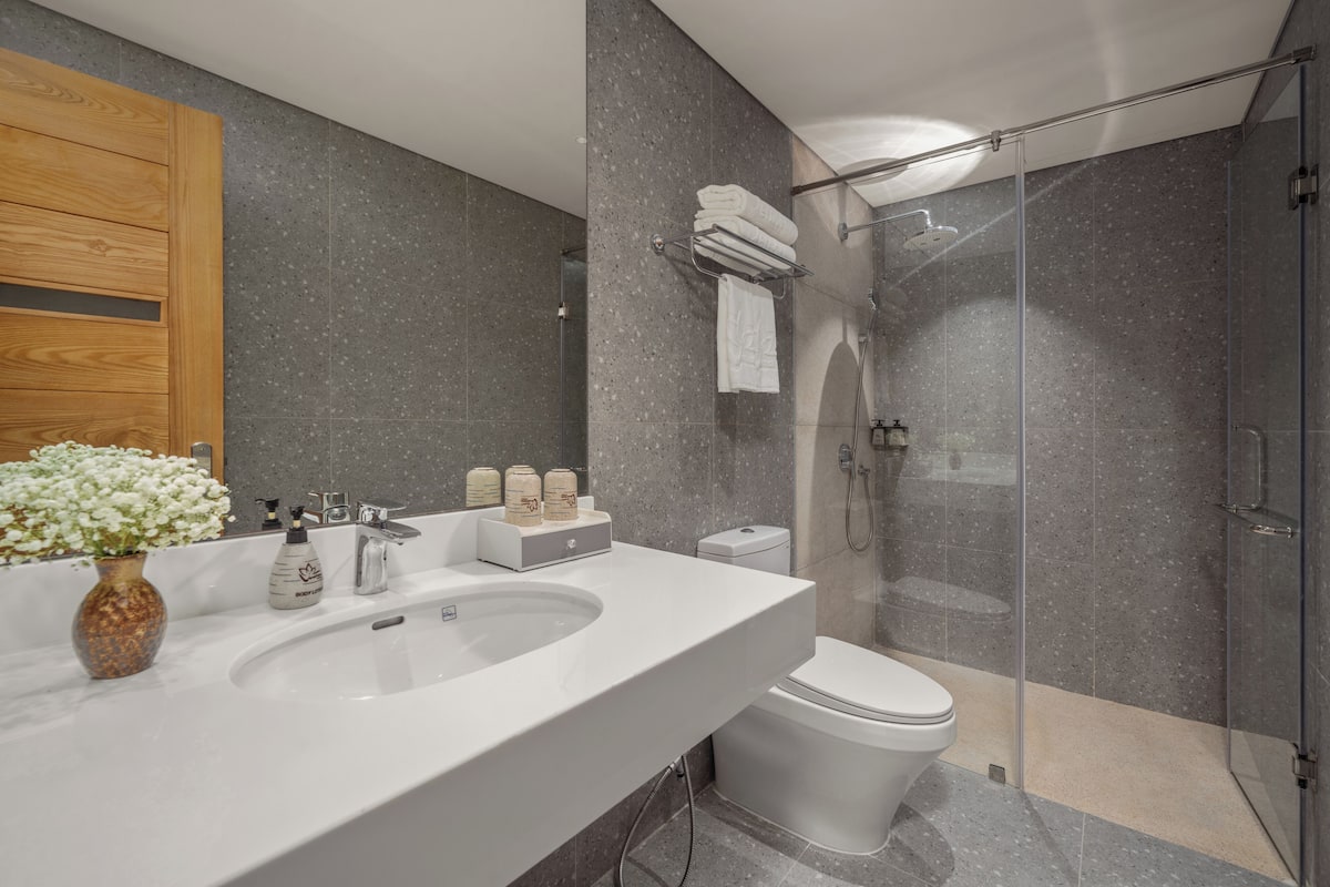 Une salle de bain moderne avec un grand lavabo, des toilettes et une douche à parois de verre.