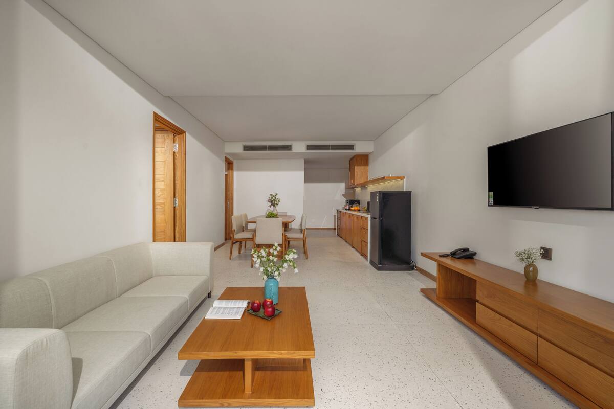 Un salon moderne comprenant un canapé, une table basse, un téléviseur, un coin cuisine et une table à manger.