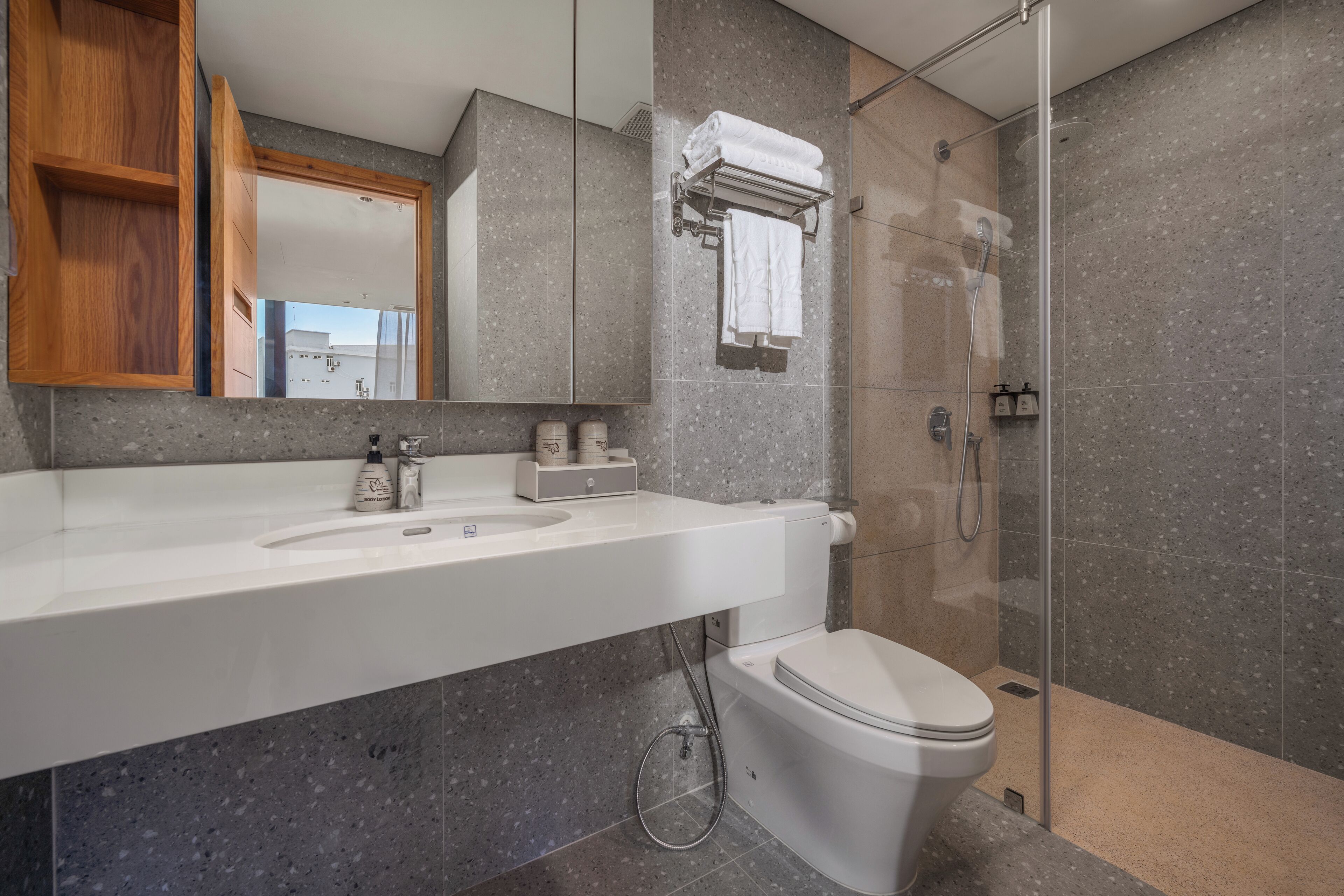 Un baño moderno con lavamanos blanco, inodoro y ducha con mampara de vidrio.