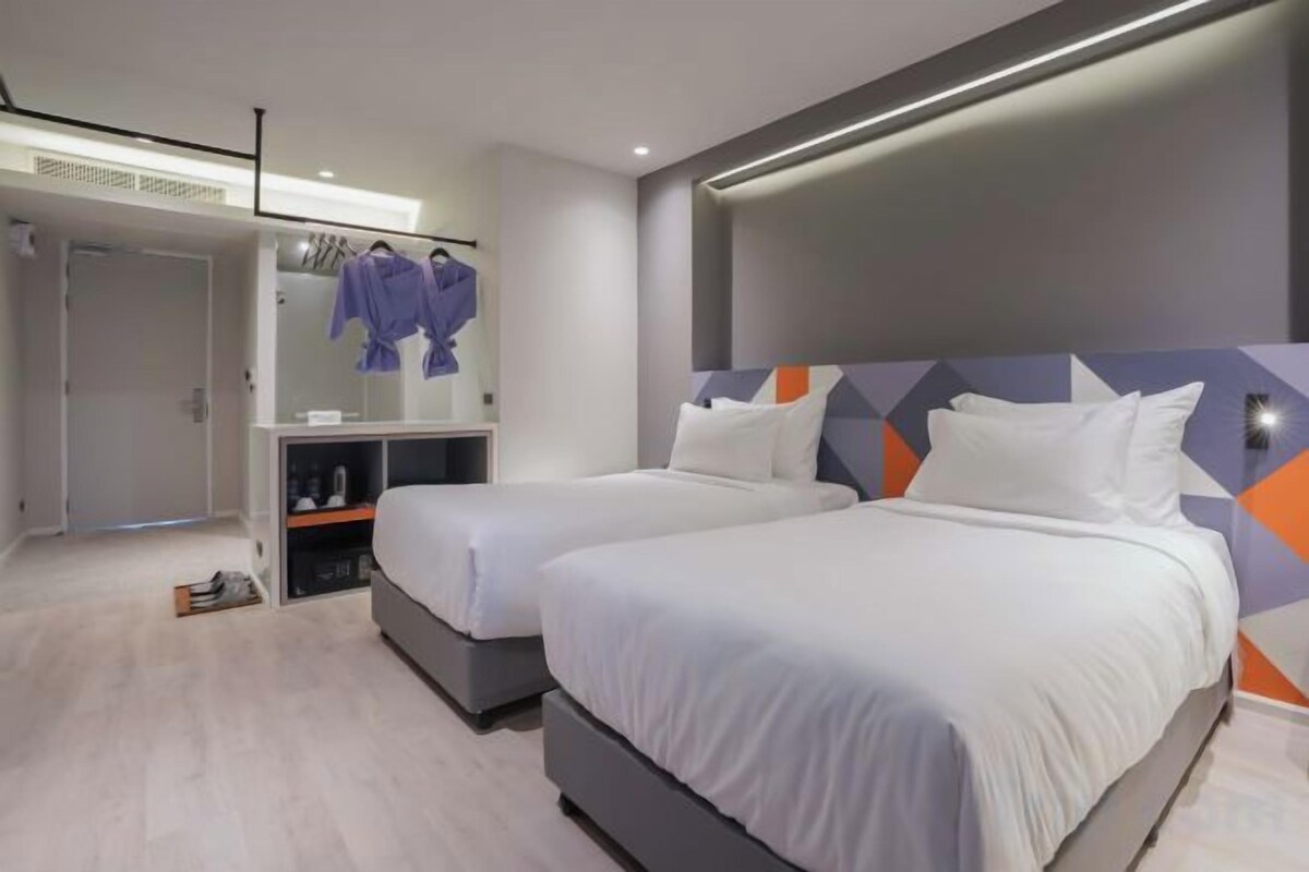 A hotel room with two beds, a wardrobe, and a mirror.