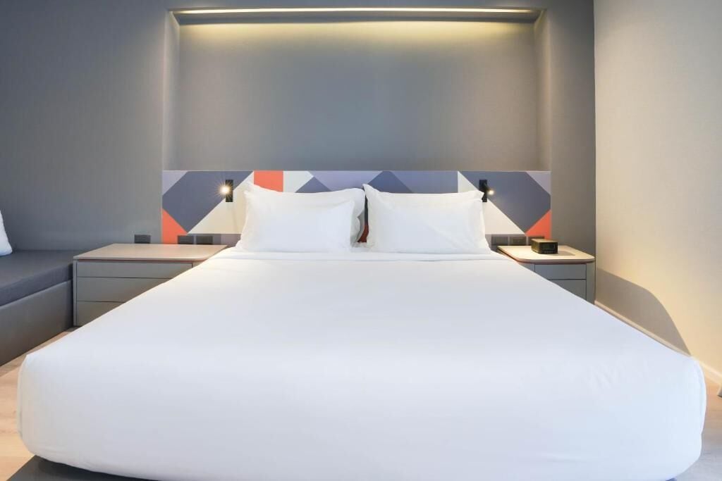 Ein modernes Hotelzimmer mit einem großen Bett, einem Nachttisch und einem Beistelltisch.
