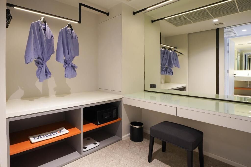 Un baño moderno con tocador, un espejo grande y dos batas colgadas en un perchero.