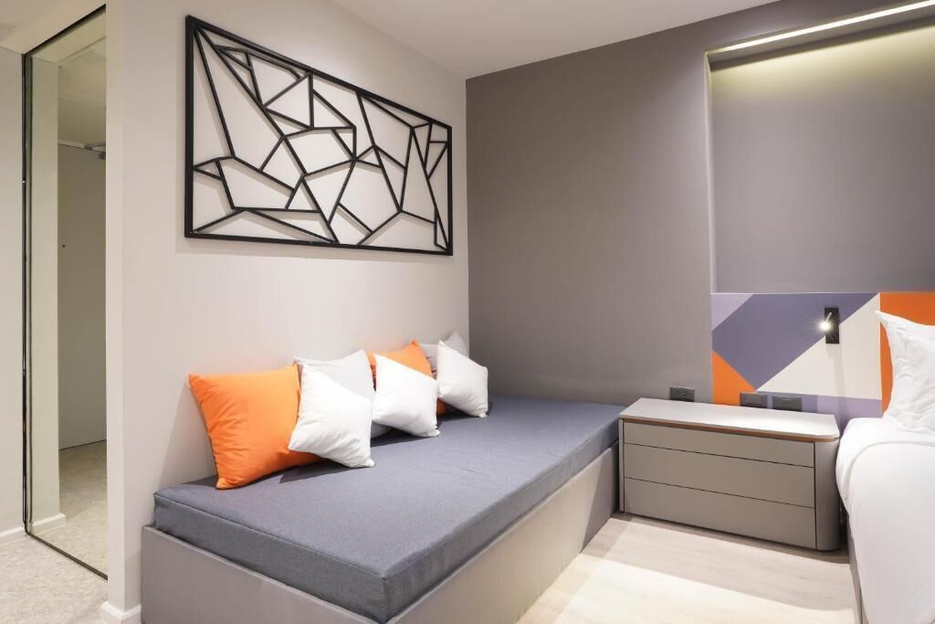 A modern bedroom with a built-in bench, a geometric wall art piece, and a bedside table with drawers.