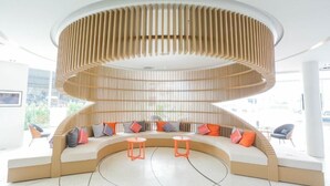 Un intérieur moderne avec un espace salon aux lignes courbes, un luminaire central et une vue sur l’extérieur.