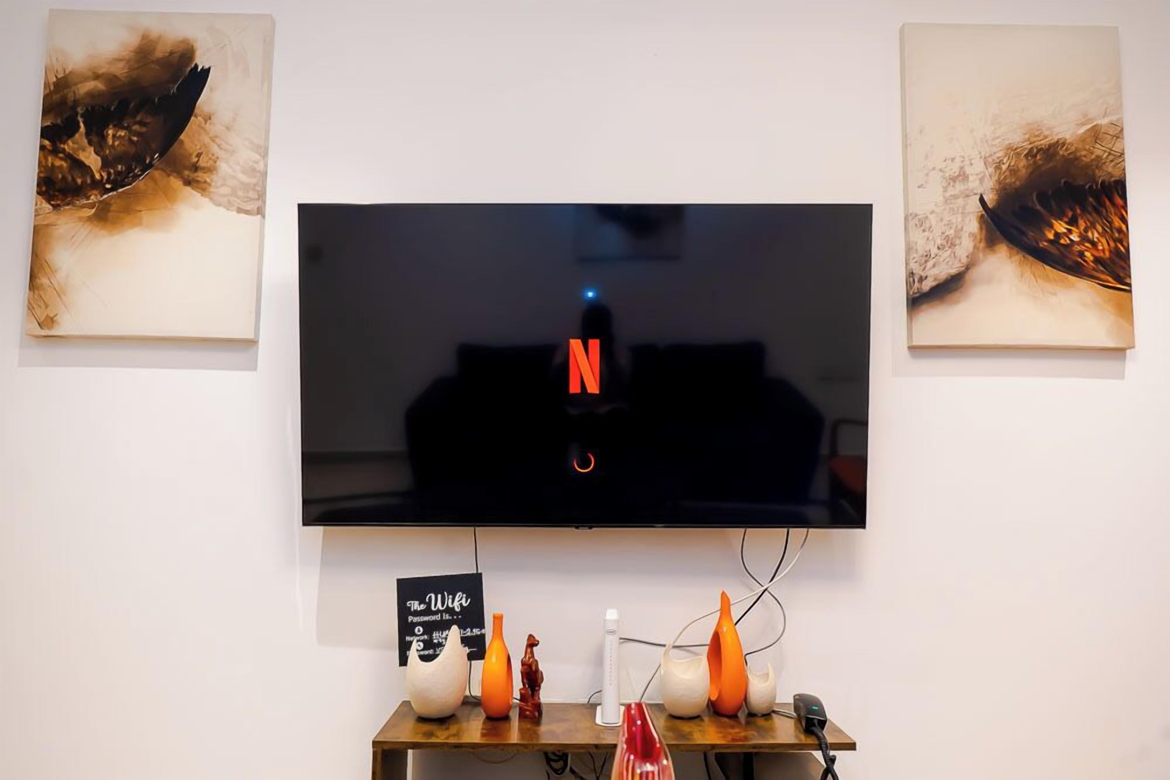 A flat-screen TV mounted on a wall with three artworks on either side.