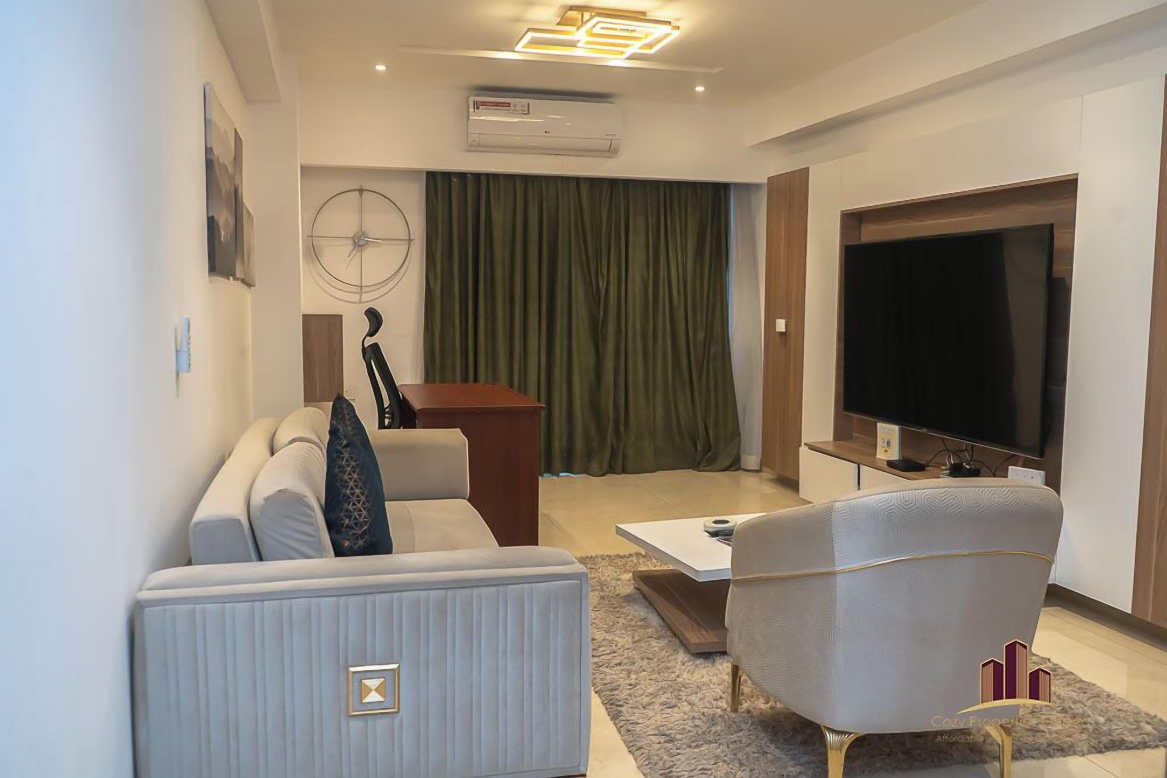 A modern living room with a sofa, armchair, coffee table, and a TV.