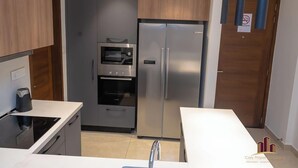 A modern kitchen with a built-in oven, microwave, and stainless steel refrigerator. - Solaris Cozy Haven (Accra)
