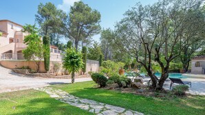 A courtyard with a swimming pool, stone pathway, and lush greenery.