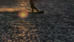 En person som åker vindsurfing i solnedgången.