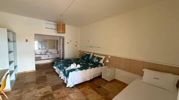 A bedroom with a bed, a bedside table, a chair, and a bathroom visible through an open door.