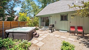 Un patio trasero con un jacuzzi, una parrilla y dos sillas rojas.