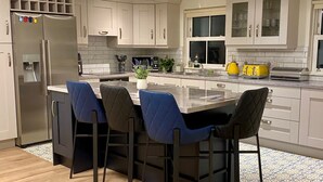 A modern kitchen with a central island, white cabinets, and a stainless steel refrigerator. - Modern Family Home (Castleisland)