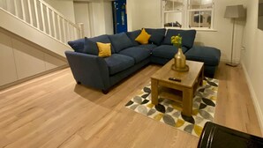 A living room with a blue sectional sofa, a wooden coffee table, and a staircase. - Modern Family Home (Castleisland)