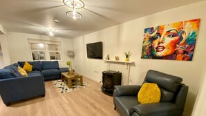 A living room with a sofa, a chair, a wooden coffee table, a fireplace, and a painting on the wall. - Modern Family Home (Castleisland)
