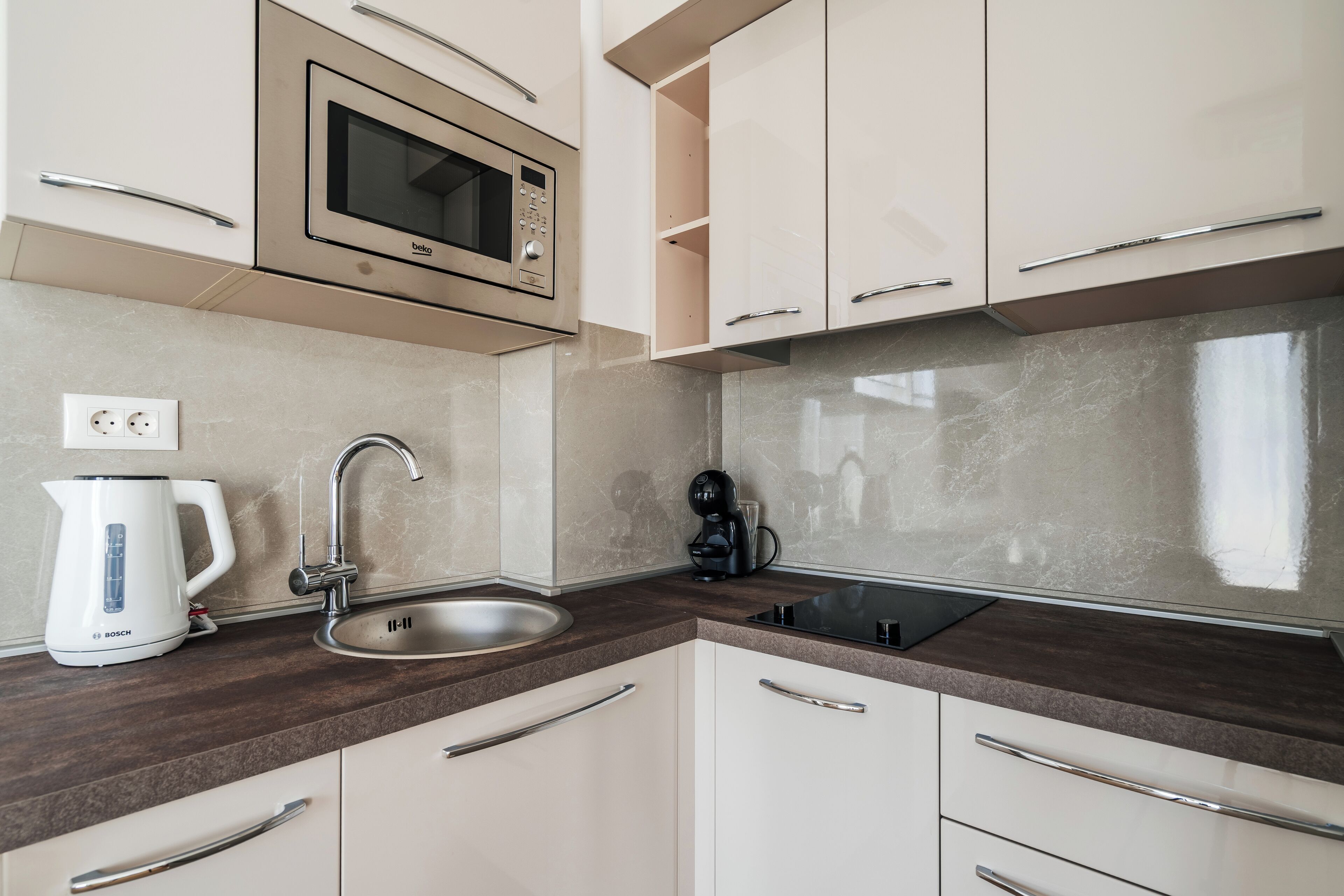 A modern kitchen with a Bosch kettle, a sink, a Bosch coffee machine, and a microwave.