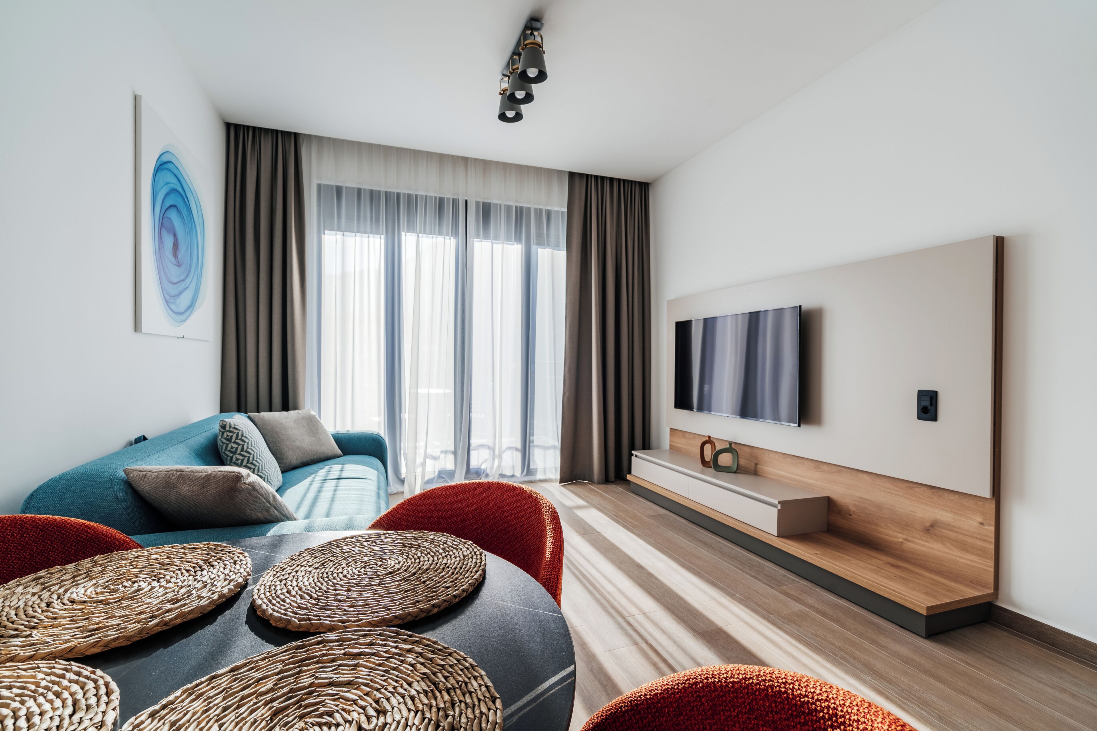 A modern living room with a sofa, TV, and woven coffee table.