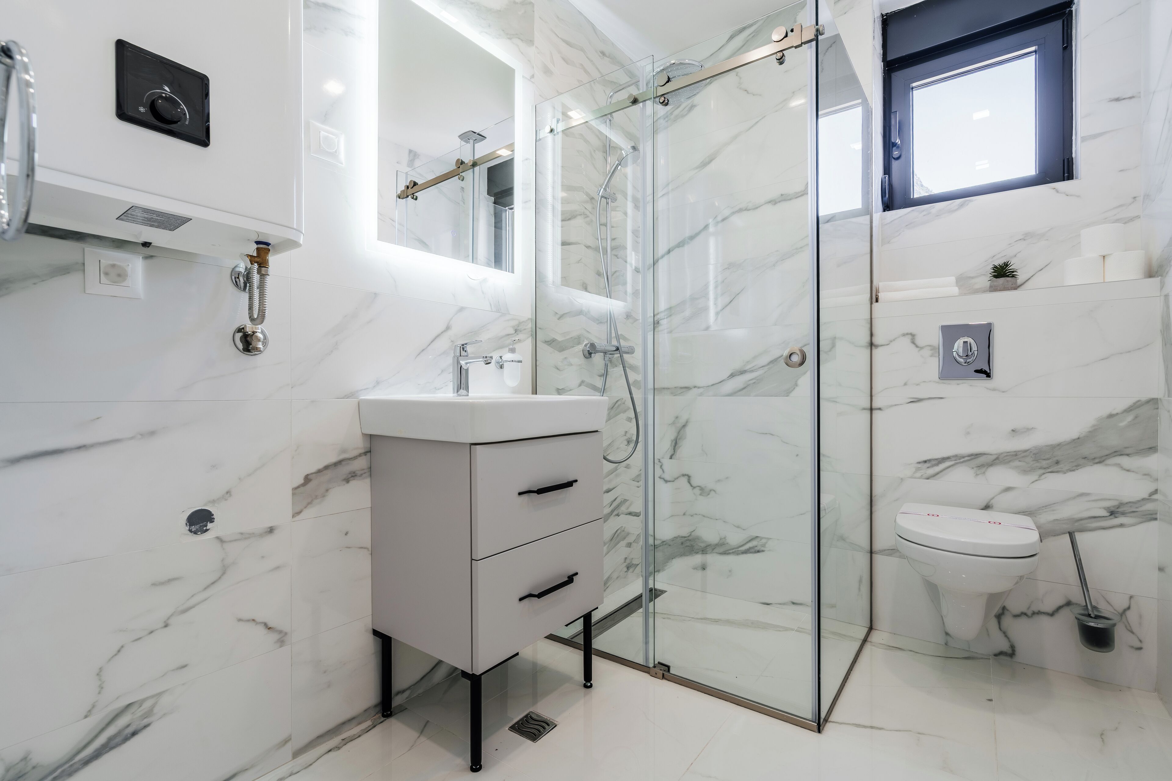 A modern bathroom with a glass shower enclosure, a white sink, and a toilet.
