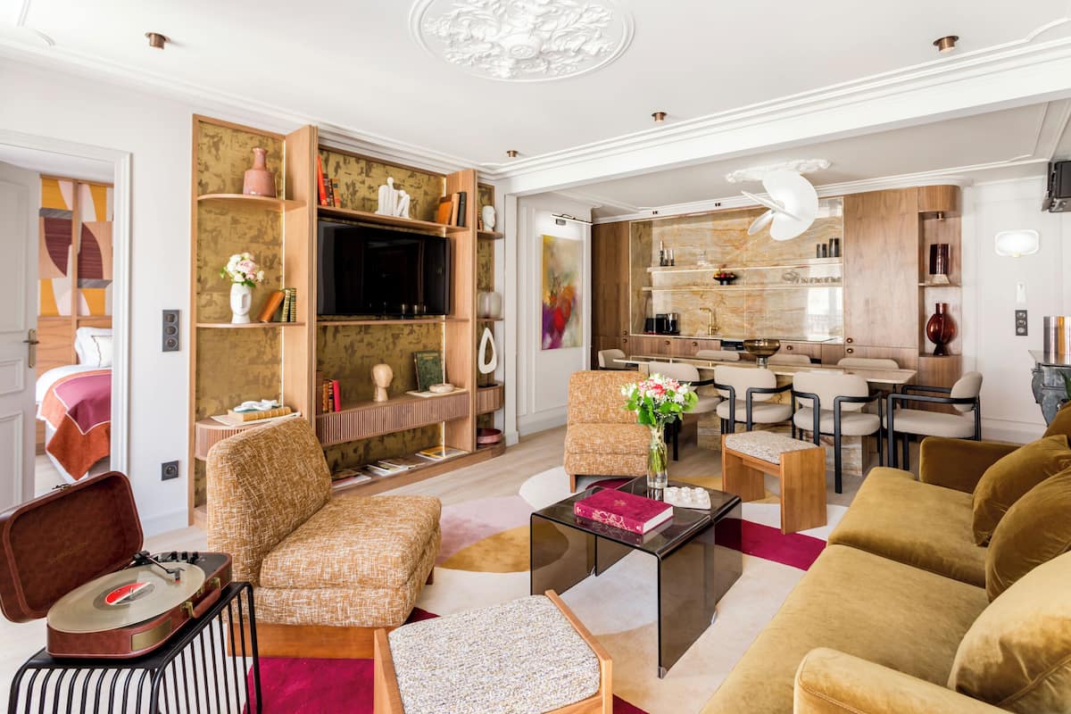 A modern living room with a sofa, armchairs, a coffee table, and a dining area with chairs and a table.